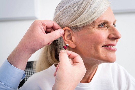 Ältere Frau erhält modernes Hörgerät zur Verbesserung ihres Hörvermögens im Alltag.